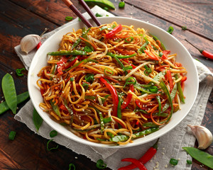 Chow mein, noodles and vegetables dish with wooden chopsticks
