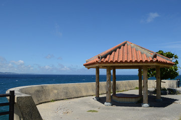 晴天の青空と青い海と沖縄の赤瓦屋根の東屋