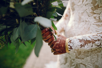 Beautiful bride in a white dress. Woman with flowers. Lady with mehendi on her hands