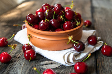 Fresh organic sweet cherries in a clay bowl on old wooden table