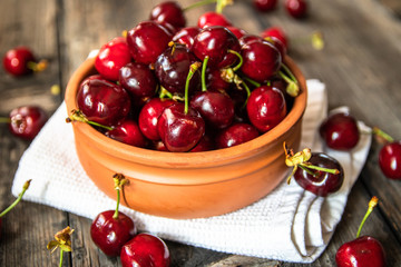 Fresh organic sweet cherries in a clay bowl on old wooden table