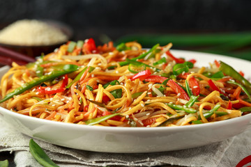 Chow mein, noodles and vegetables dish with wooden chopsticks