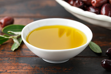 Extra virgin olive oil and kalamata olives on rustic wooden background