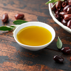 Extra virgin olive oil and kalamata olives on rustic wooden background