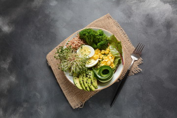 Green vegetarian buddha bowl lunch with boiled egg, avocado, corn, arugula beet leaves,fresh cucumber, buckwheat, broccoli sprouts.Healthy vegan food concept 