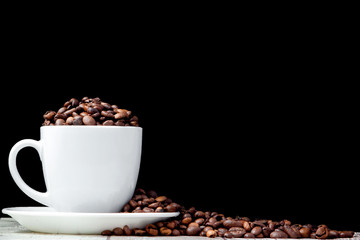 Black coffee in white cup and coffee beans on black background. Top view, space for text