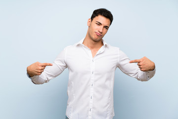 Handsome man over blue wall proud and self-satisfied