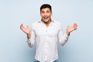 Handsome man over blue wall with shocked facial expression