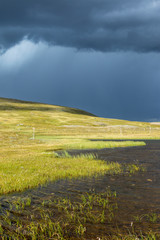Lake in the wild with dark rain clouds at the sky