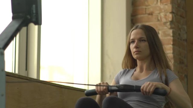 Slow Motion Woman Working Out On Rowing Machine At The Gym