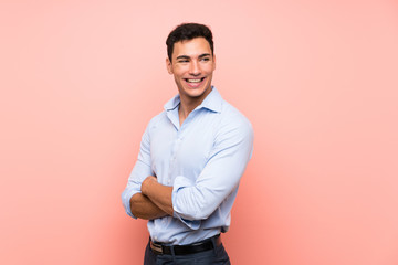 Handsome man over pink background with arms crossed and happy