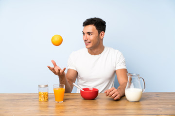 Handsome man in having breakfast and holding an orange