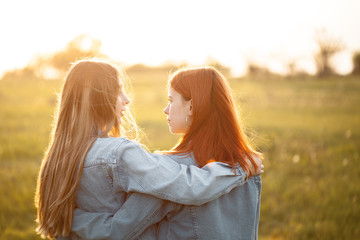 Fototapeta premium Two young women standing together under sunset. Best friends