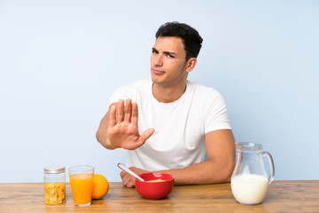 Handsome man in having breakfast making stop gesture with her hand