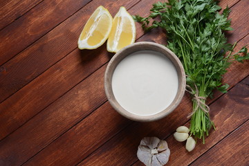 Tahini sauce made from sesame seeds in bowl with parsley on wooden background