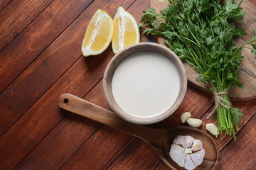 Tahini sauce made from sesame seeds in bowl with parsley on wooden background