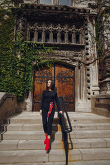 stylish brunette standing next to the entance to a building at University of Chicago