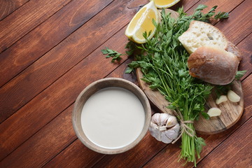 Tahini sauce made from sesame seeds in bowl with parsley on wooden background