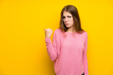 Fototapeta premium Young woman with long hair over isolated yellow wall unhappy and pointing to the side
