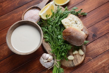 Tahini sauce made from sesame seeds in bowl with parsley on wooden background