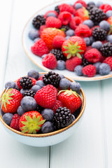 Fresh berry salad on blue dishes. Vintage wooden background.