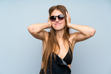 Young woman in bikini in summer holidays covering both ears with hands