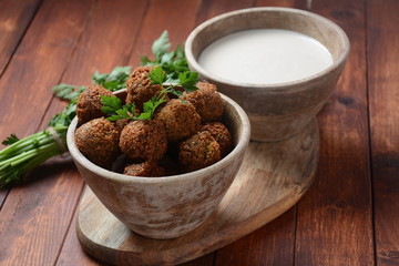 Falafel balls with parsley in wooden bowl with tahini sauce. Vegan healthy food 