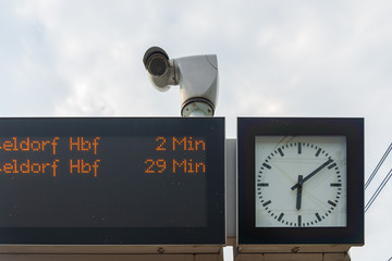 Outdoor low angle view of clock, security camera and black led display which show train or tram...