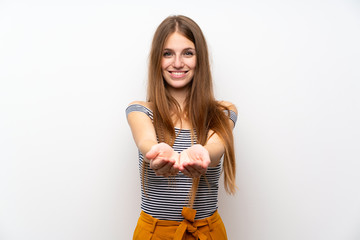 Young woman with long hair over isolated white wall holding copyspace imaginary on the palm to...