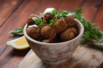 Falafel balls with parsley in wooden bowl with tahini sauce. Vegan healthy food