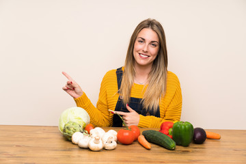 Fototapeta premium Woman with lots of vegetables pointing finger to the side