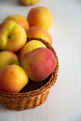 Close-up of apricots in basket on white wooden background in vertical