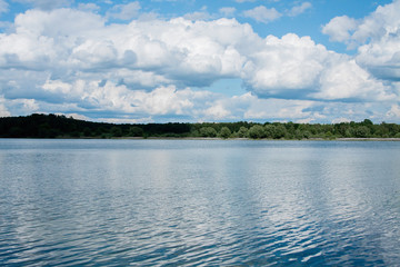 white clouds on a blue sky on a Sunny summer day forest shore