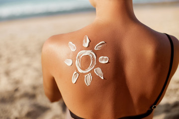 Woman Applying Sun Cream on Tanned  Shoulder In Form Of The Sun. Sun Protection.Sun Cream. Skin and...