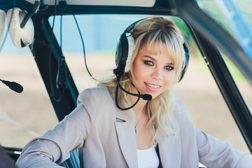 Female pilot in cockpit of helicopter before take off. Young woman helicopter pilot.