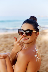 Beautiful Woman smile applying sun cream on face. Skincare. Body Sun protection. sunscreen. Female...