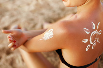 Beautiful Woman smile applying sun cream  on shoulder. Skincare. Body Sun protection....