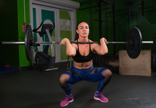 Strong muscular girl training in the gym with a barbell
