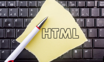 HTML Hyper Text Markup Language. Paper width word HTML and pencil on laptop keyboard