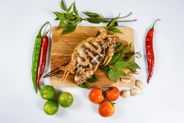 Raw crab on wooden plate with lemon, basil, pepper, tomato and garlic at white background, Sea food.