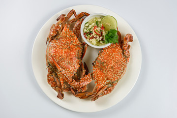 Steamed blue crab on white plate with spicy seafood sauce