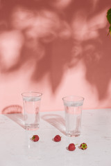 Glass of cold raspberry cider with fresh berries on light background