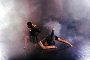 Modern dance couple twisting their legs and lening close to the ground, touching and combining...