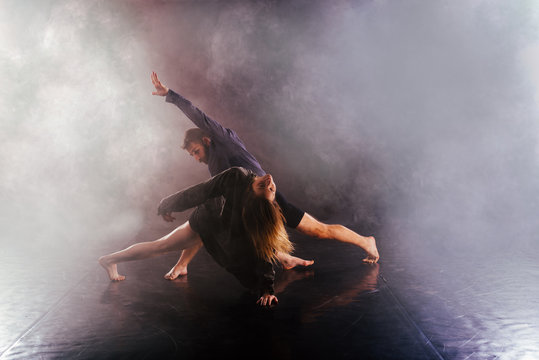 Modern dance couple twisting their legs and lening close to the ground, touching and combining their bodies in extremely unique modern dance experience. © qunica.com