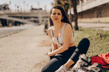 Happy joyful young woman wearing roller skates sitting in town