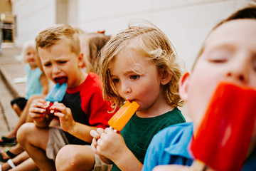 Group of Kids Eating Frozen Colorful Popsicles in the Summer