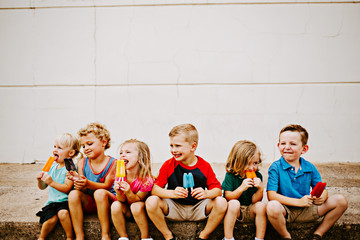 Group of Kids Eating Frozen Colorful Popsicles in the Summer
