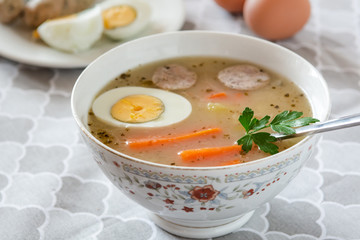 Traditional Polish soup Zurek with white sausage and egg.