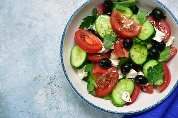 Traditional greek vegetable salad in a white bowl. Top view with copy space.