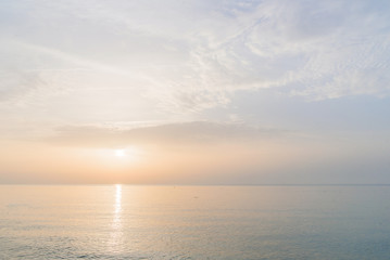 Fototapeta na wymiar Sunrise at the sea beach. Calm sea without waves in the morning.